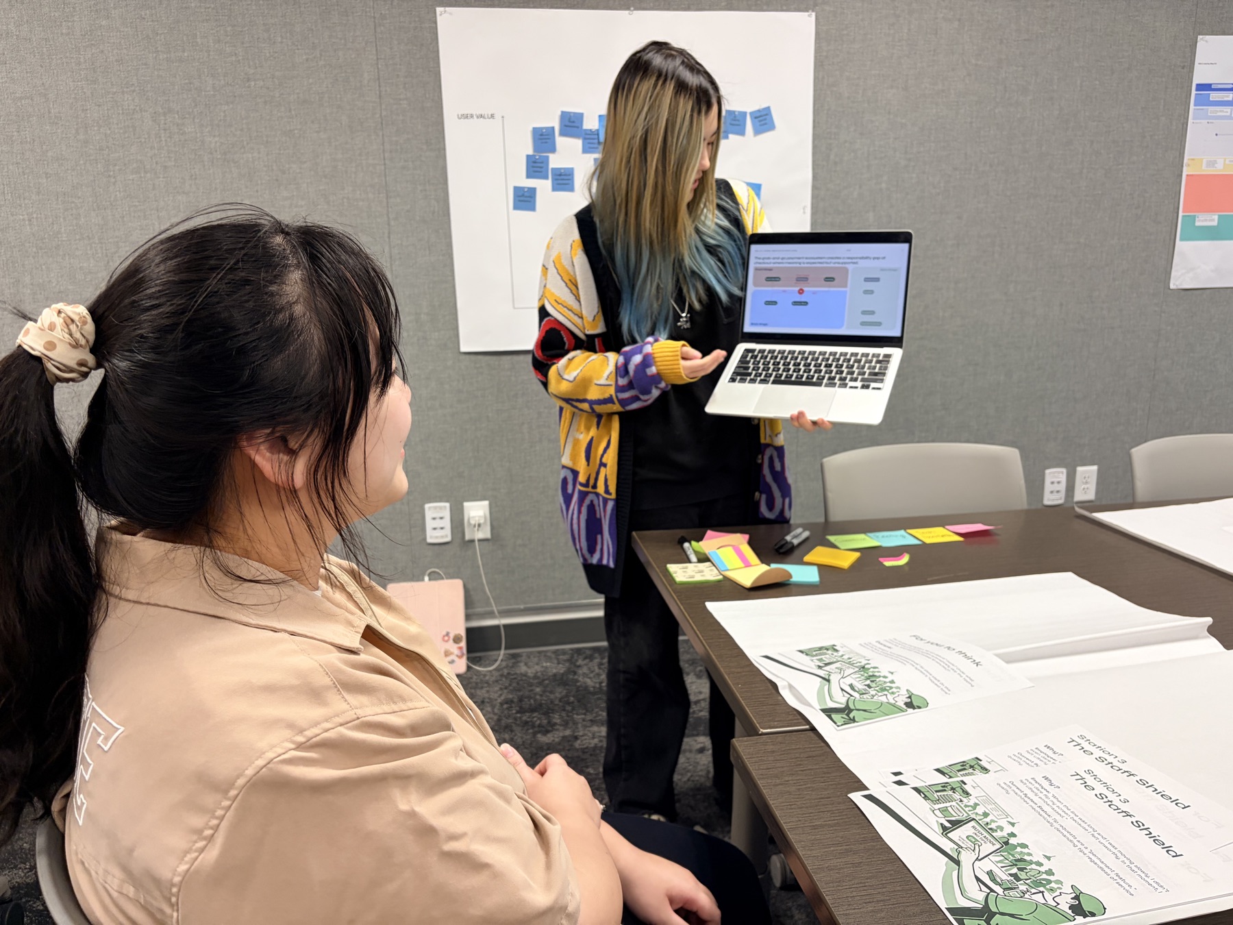 Workshop facilitator showing a participant the Honest Receipt card on a laptop